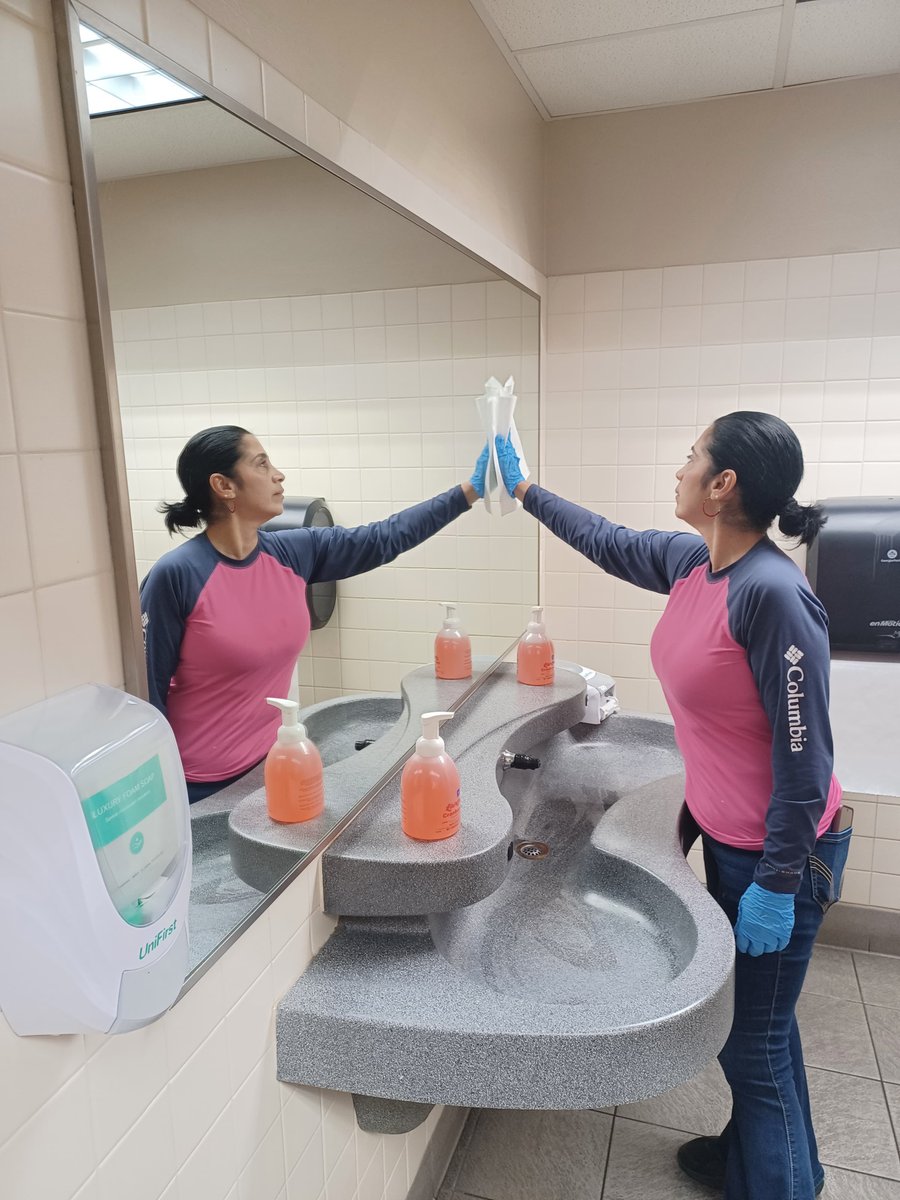 Cleaner wiping a mirror in a bathroom